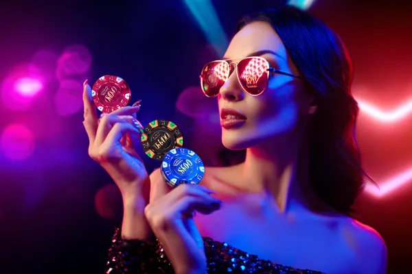 Permainan WAJA CASINO — Terokai koleksi klasik kasino kami Seorang wanita tersenyum bermain permainan dalam talian di komputer riba dengan elemen kasino neon di sekelilingnya, menunjukkan koleksi permainan WAJA CASINO.